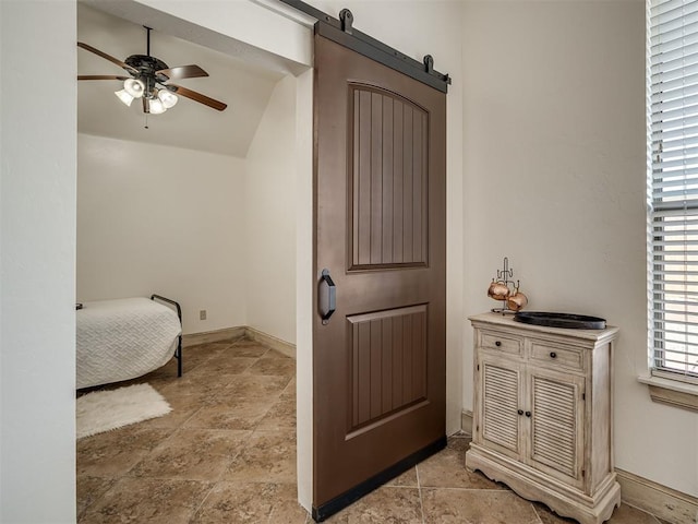 bedroom with a barn door, baseboards, and a ceiling fan