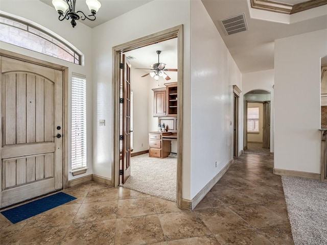 carpeted entrance foyer featuring arched walkways, visible vents, plenty of natural light, and baseboards