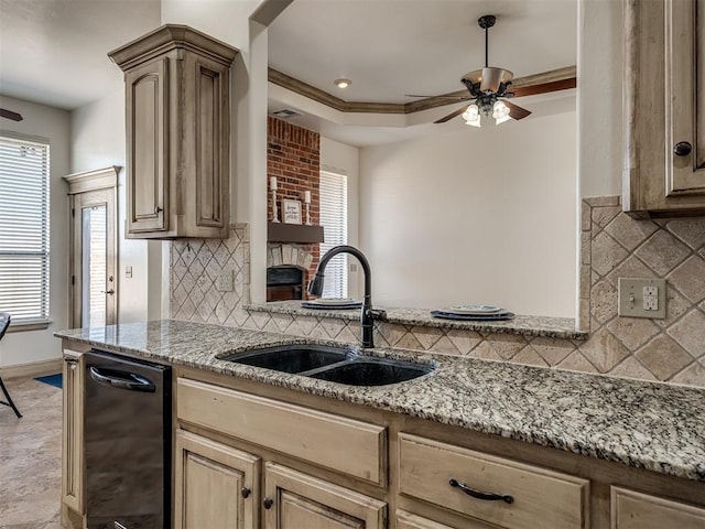 kitchen with a ceiling fan, a sink, light stone counters, crown molding, and a raised ceiling