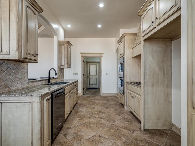 kitchen with light stone counters, baseboards, a sink, black appliances, and tasteful backsplash