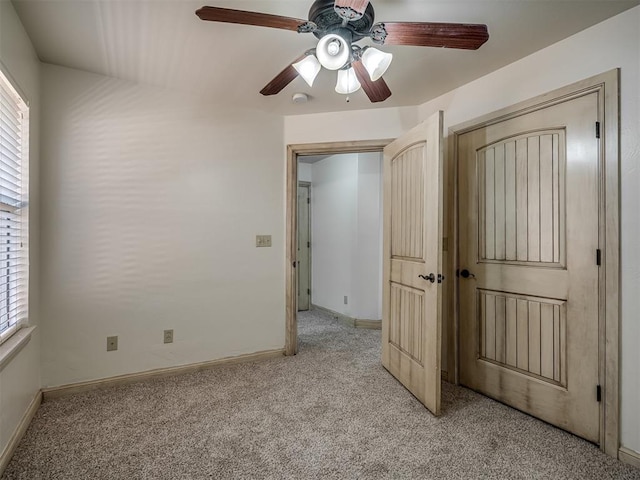 unfurnished bedroom featuring light carpet, a ceiling fan, and baseboards