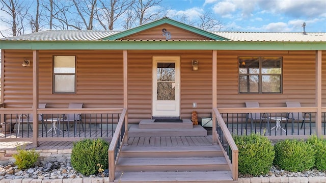 view of front of house with log veneer siding, covered porch, and metal roof