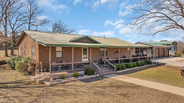 view of front facade featuring a front lawn, driveway, a porch, faux log siding, and an attached garage