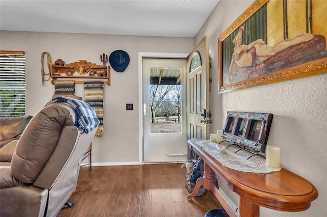 doorway to outside with a fireplace, wood finished floors, baseboards, and a textured ceiling