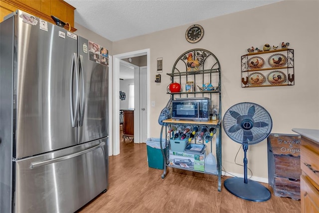 kitchen with wood finished floors, baseboards, freestanding refrigerator, and a textured ceiling