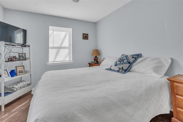 bedroom with wood finished floors, visible vents, and a textured ceiling