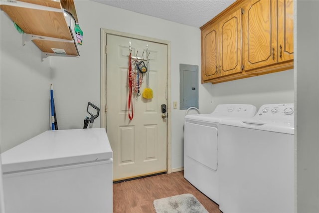 laundry area with light wood-type flooring, electric panel, cabinet space, independent washer and dryer, and a textured ceiling