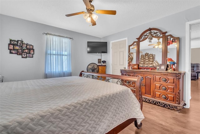 bedroom with light wood-type flooring, a textured ceiling, and a ceiling fan