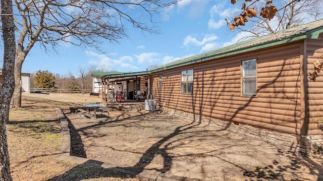 view of side of property with log veneer siding, metal roof, and central AC unit