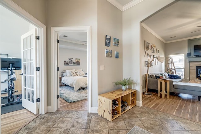 corridor featuring crown molding, visible vents, baseboards, and tile patterned floors