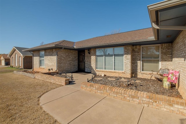 view of front of property featuring brick siding and a shingled roof