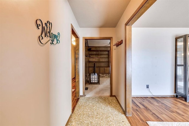 corridor featuring baseboards and light wood finished floors