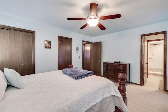 bedroom with connected bathroom, baseboards, ceiling fan, multiple closets, and light carpet