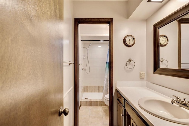 bathroom with vanity, tile patterned floors, toilet, and a tile shower