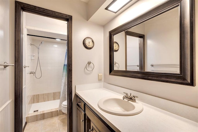 full bathroom featuring a tile shower, tile patterned flooring, toilet, and vanity