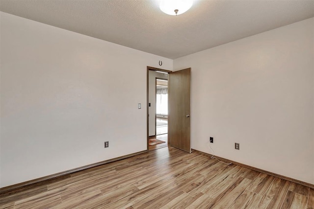 unfurnished room featuring baseboards, a textured ceiling, and light wood finished floors