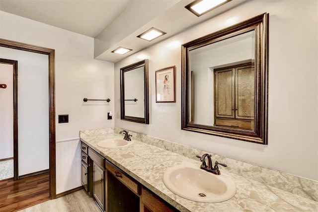 full bath featuring double vanity, wood finished floors, and a sink