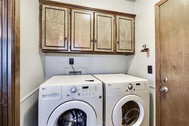 laundry room with washer and dryer, cabinet space, and a wainscoted wall