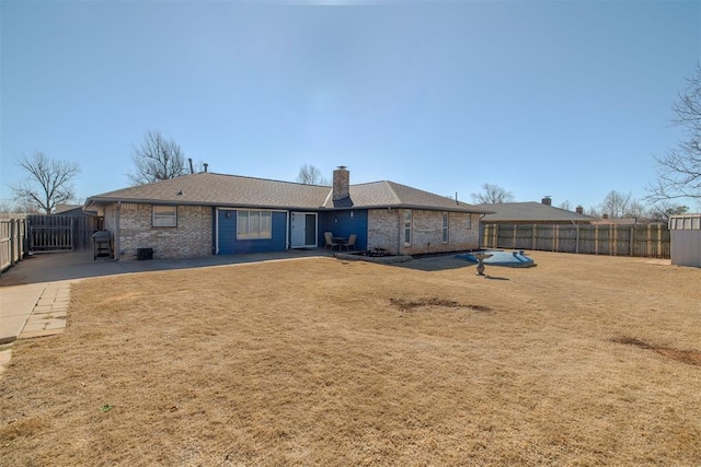 back of property featuring brick siding, a chimney, a lawn, and fence