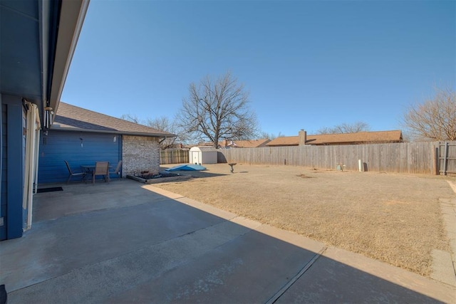 view of yard featuring an outbuilding, a fenced backyard, a storage shed, and a patio