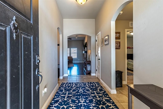 interior space featuring light tile patterned flooring, visible vents, arched walkways, and baseboards