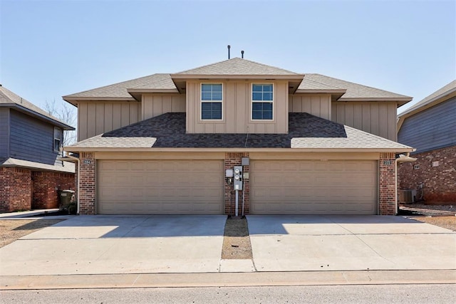 traditional home featuring a garage, brick siding, driveway, and a shingled roof