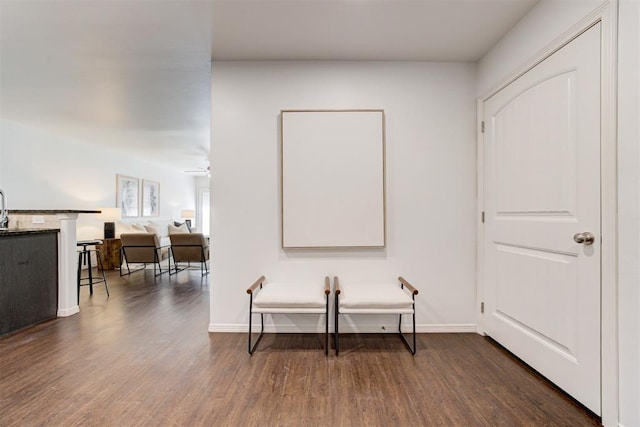 corridor with baseboards, dark wood-style flooring, and a sink