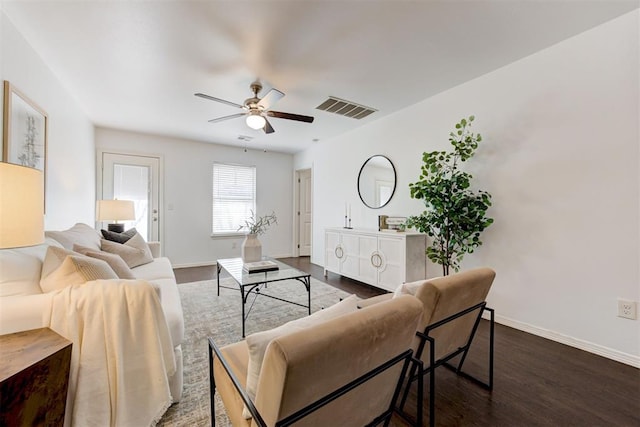 living room with dark wood-type flooring, baseboards, visible vents, and ceiling fan