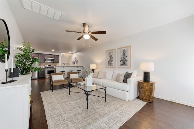 living area featuring dark wood-type flooring, baseboards, and ceiling fan