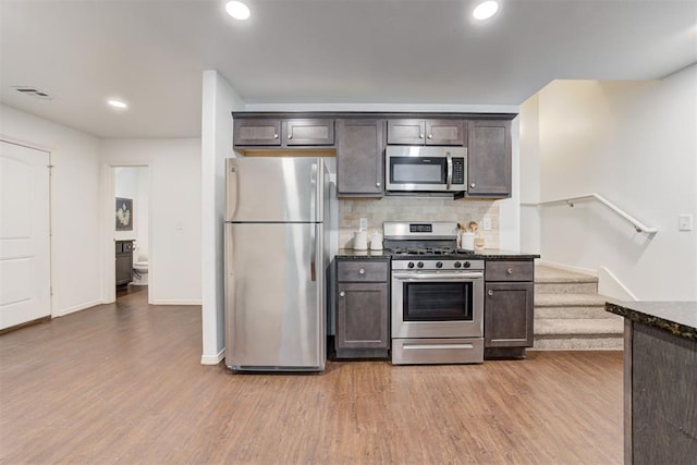 kitchen featuring decorative backsplash, dark brown cabinetry, wood finished floors, and stainless steel appliances