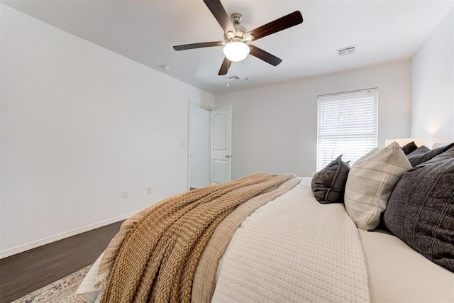 bedroom with ceiling fan, visible vents, baseboards, and wood finished floors