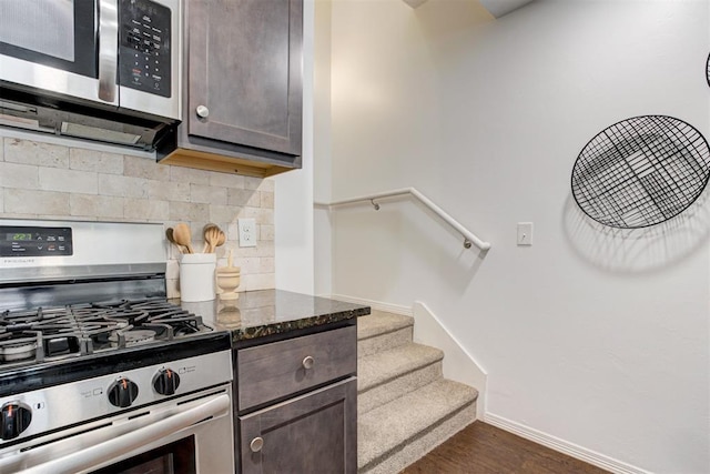 kitchen featuring dark wood-style floors, dark stone counters, appliances with stainless steel finishes, decorative backsplash, and dark brown cabinets