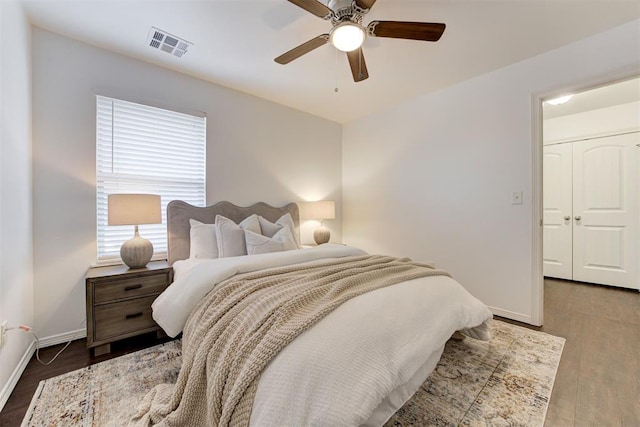 bedroom featuring ceiling fan, wood finished floors, visible vents, and baseboards