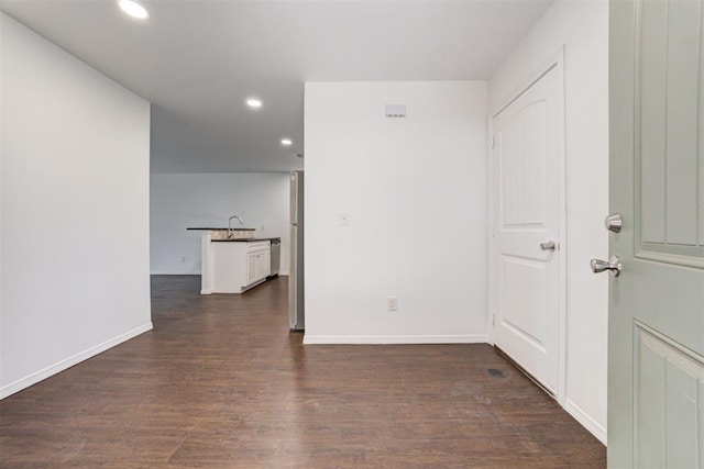 spare room with a sink, baseboards, recessed lighting, and dark wood-style flooring