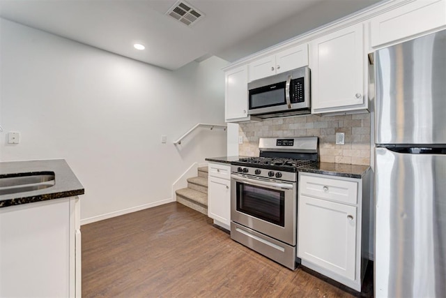 kitchen featuring visible vents, dark wood-type flooring, white cabinetry, appliances with stainless steel finishes, and decorative backsplash