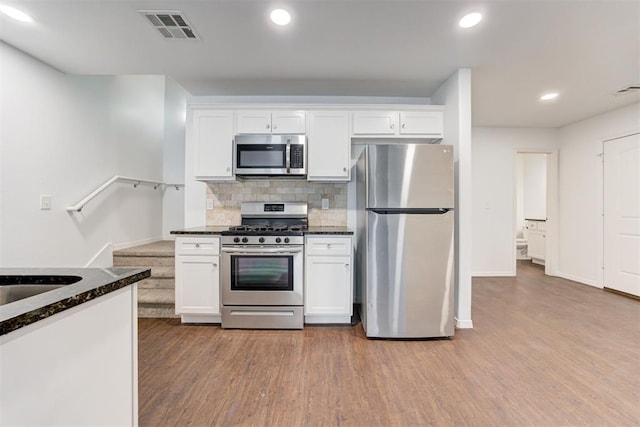 kitchen with stainless steel appliances, visible vents, wood finished floors, and white cabinetry