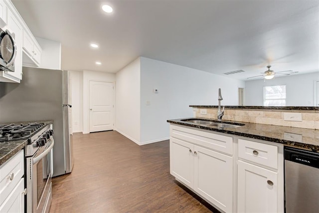 kitchen featuring dark stone countertops, visible vents, dark wood finished floors, a sink, and appliances with stainless steel finishes