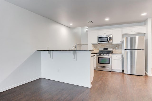 kitchen with stainless steel appliances, a kitchen breakfast bar, dark wood-type flooring, and visible vents