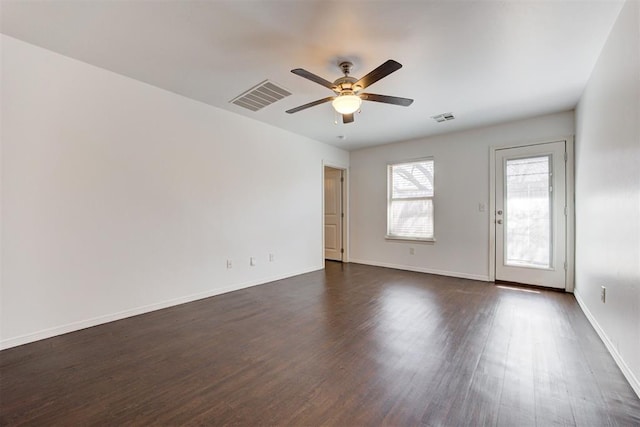 spare room with visible vents, baseboards, dark wood-style floors, and a ceiling fan