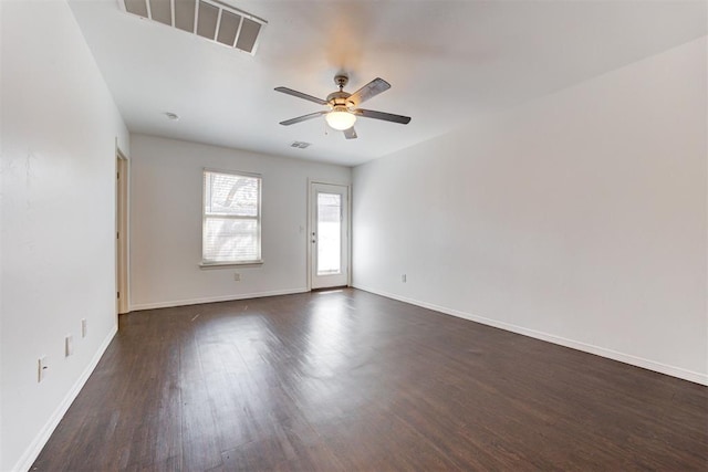 unfurnished room with dark wood finished floors, a ceiling fan, visible vents, and baseboards