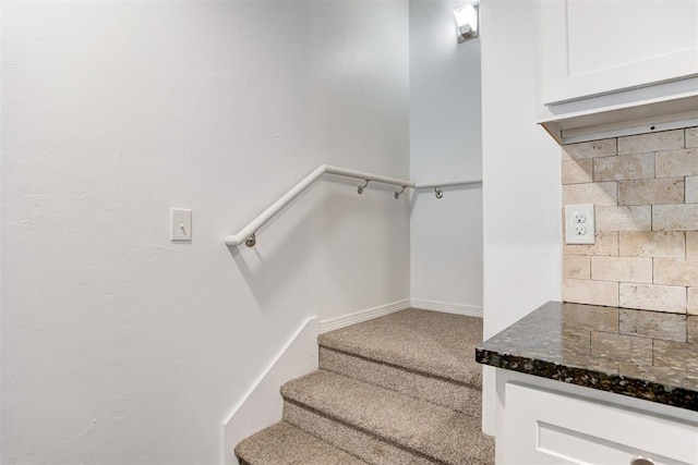 stairway featuring baseboards and carpet floors