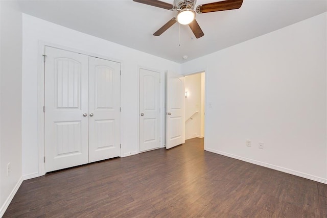 unfurnished bedroom with a closet, baseboards, dark wood finished floors, and a ceiling fan