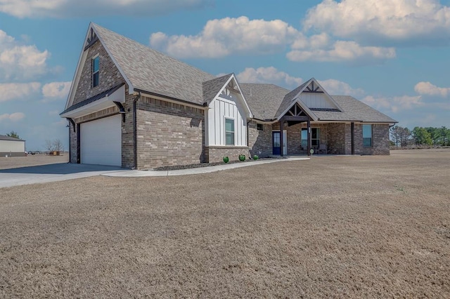 view of front facade with driveway, roof with shingles, an attached garage, board and batten siding, and brick siding