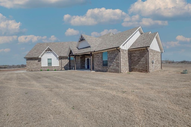 view of front of property with brick siding, board and batten siding, and roof with shingles