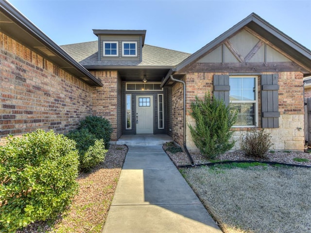 entrance to property with brick siding, stone siding, and roof with shingles