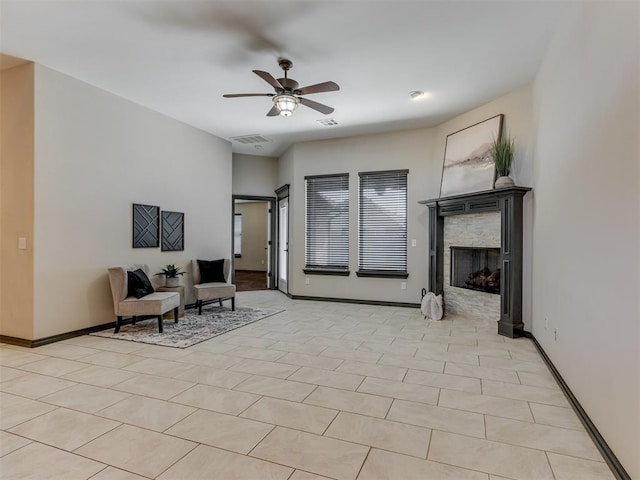 interior space featuring a fireplace, baseboards, visible vents, and ceiling fan