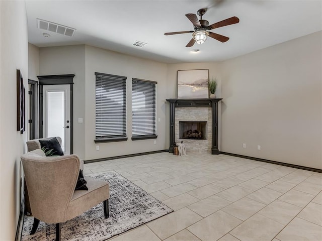 living area with visible vents, ceiling fan, a fireplace, and baseboards