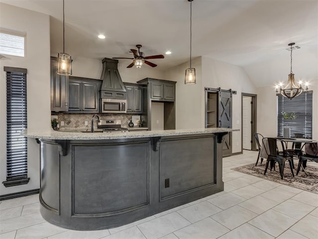 kitchen featuring a barn door, a breakfast bar area, a peninsula, and appliances with stainless steel finishes