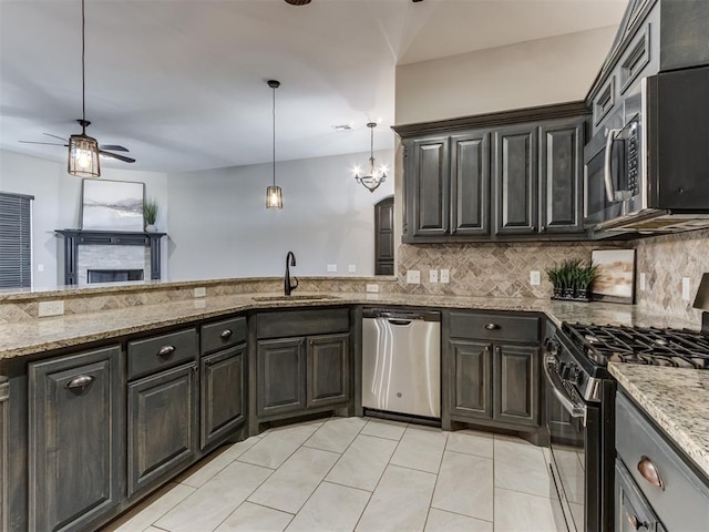 kitchen featuring a sink, backsplash, appliances with stainless steel finishes, light stone countertops, and ceiling fan