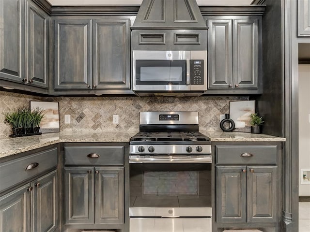 kitchen with light stone countertops, backsplash, and appliances with stainless steel finishes